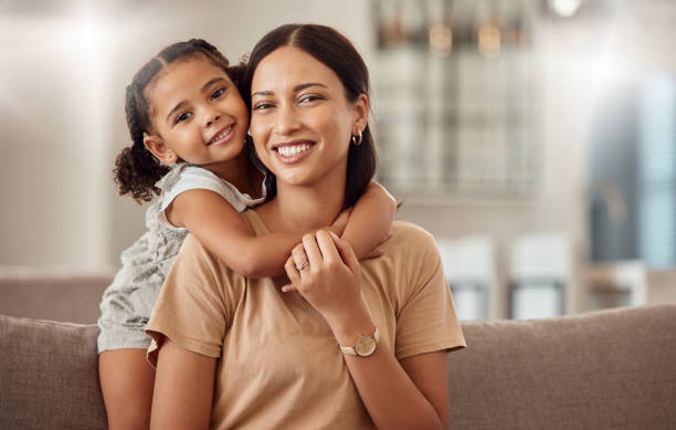 Black family, hug and portrait of child with mother, mom or mama bond, relax and enjoy quality time together. Love, happy family and woman with kid girl smile, care or lounge on home living room sofa stock photo