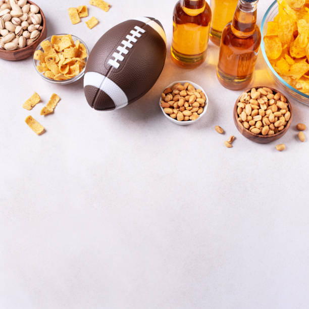 beer in bottle and snack on concrete table with rugby ball, game night food - beer nuts imagens e fotografias de stock