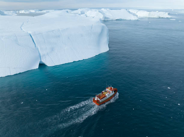 istock small boat sailing between big icebergs 1446886317