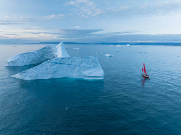istock sailboat with red sails sailing among large icebergs 1446886325