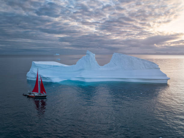 istock sailboat with red sails sailing among large icebergs 1446886345