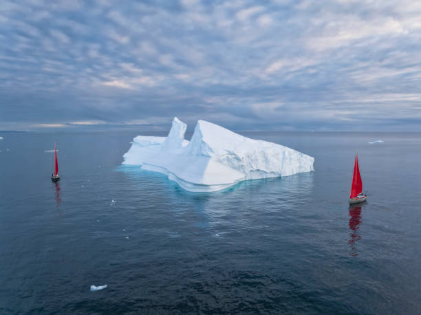 istock sailboat with red sails sailing among large icebergs 1446886354