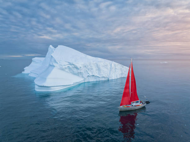 istock sailboat with red sails sailing among large icebergs 1446886360