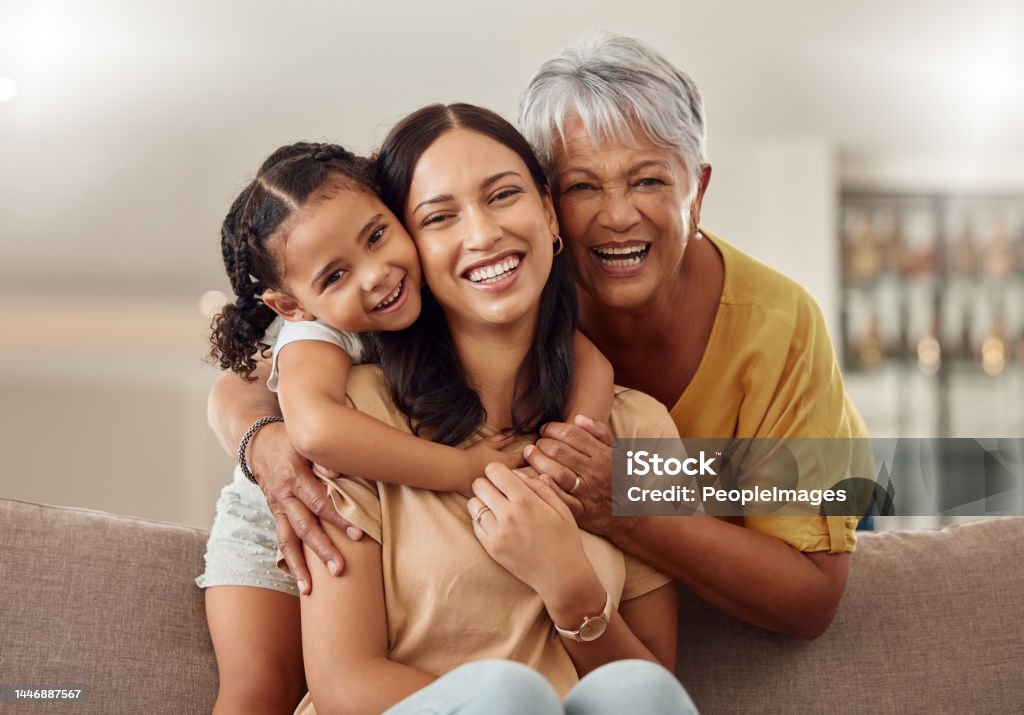 Grandmother, mom and child hug in a portrait for mothers day on a house sofa as a happy family in Colombia. Smile, mama and elderly woman love hugging young girl or kid and enjoying quality time Family Stock Photo