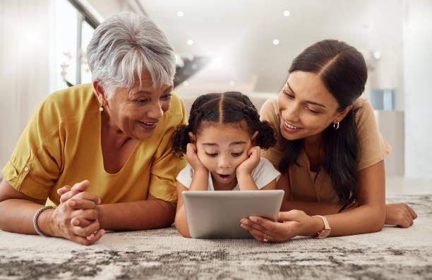 grandmother, mother and child with a tablet streaming a movie while relaxing together. shocked, surprised and happy family watching a online video on social media with digital  device in a home - digital tablet women enjoyment happiness imagens e fotografias de stock