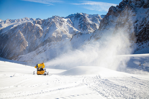 Snow cannon in action at mountain ski resort.