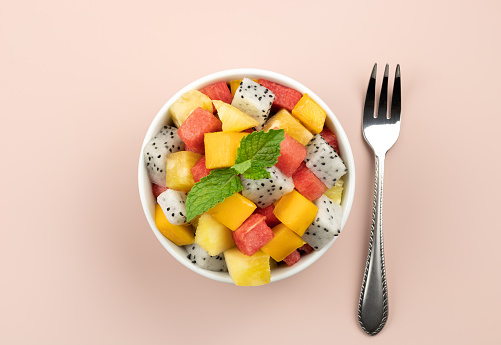 Fruit salad with mango, watermelon, dragon fruit, pineapple, mint on a pink background. Thai tropical fruit salad. High quality photo
