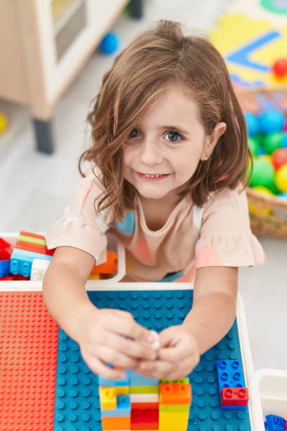 istock Adorable hispanic girl playing with construction blocks sitting on table at kindergarten 1446888420