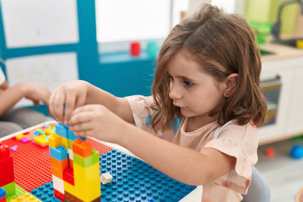 istock Adorable hispanic girl playing with construction blocks sitting on table at kindergarten 1446888425
