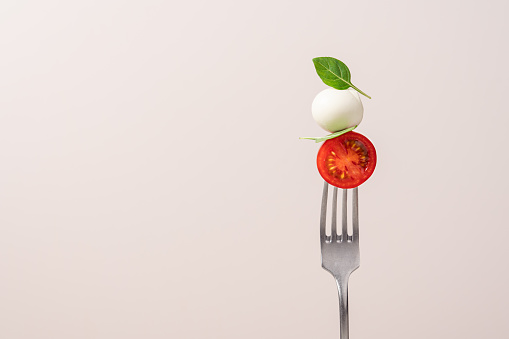 Fork with tomato, mozzarella cheese and basil. Italian food concept