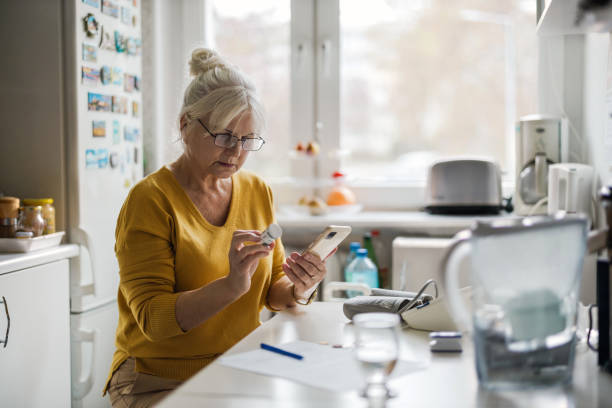 une femme âgée vérifie son ordonnance avec un téléphone cellulaire - healthcare and medicine home interior medicine geriatrics photos et images de collection