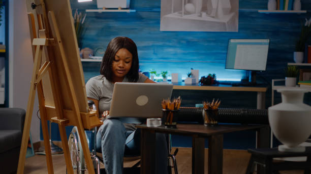 istock Black artist with handicap typing on laptop computer 1446889987