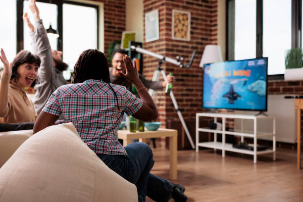 istock Multiracial friends celebrating space game simulator victory played on modern console device. 1446892550