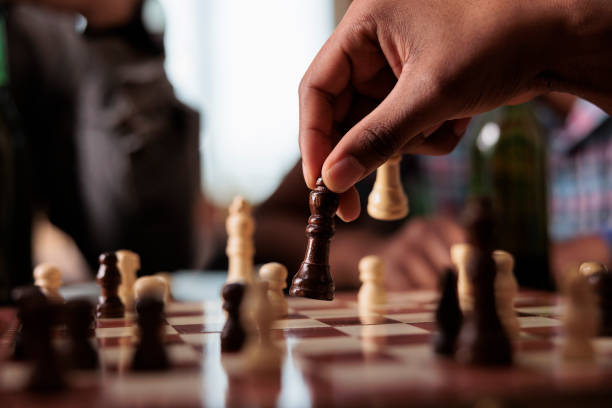 istock Close up of hand moving chess piece on chessboard while sitting at table. 1446893148