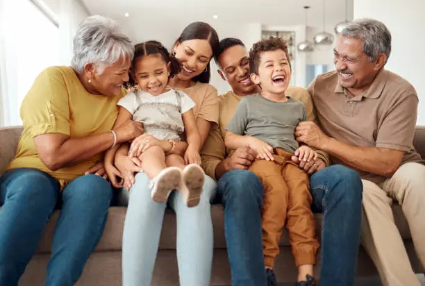 Photo of Happy, big family and quality time bonding of children, parents and grandparents together on a sofa. Laughing kids having fun with mom, dad and grandparent on a home living room couch with happiness