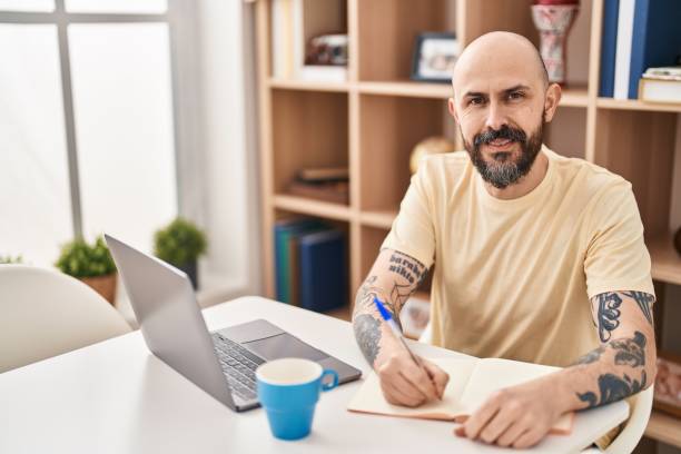 istock Young bald man sitting on table studying at home 1446894156