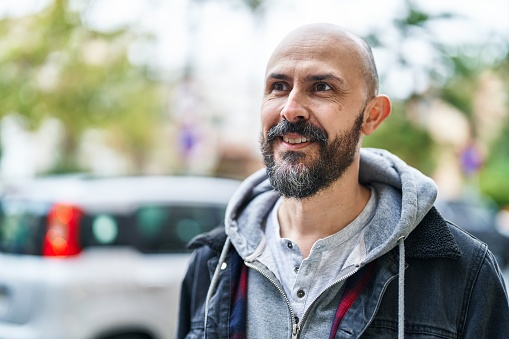 Young bald man smiling confident looking to the side at street