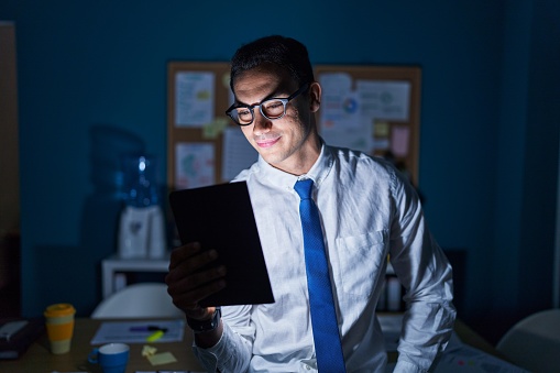 Young hispanic man business worker using touchpad standing at office