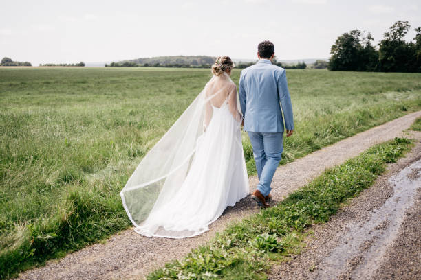 istock bride and groom walk on a field path in nature during photo shoot 1446895827