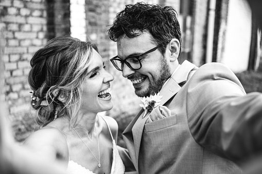black and white photo of bride and groom take selfie on wedding day