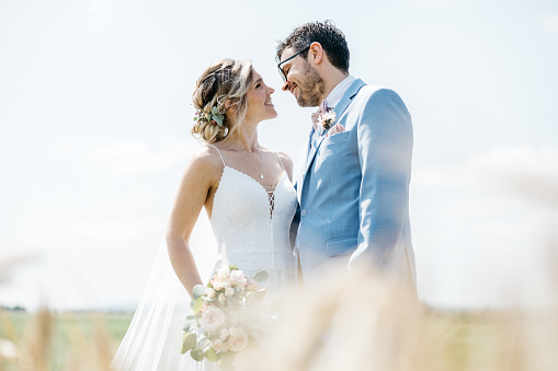 wedding day. beautiful bride in white long dress and young groom wearing in black suit are hugging in historic europe town.