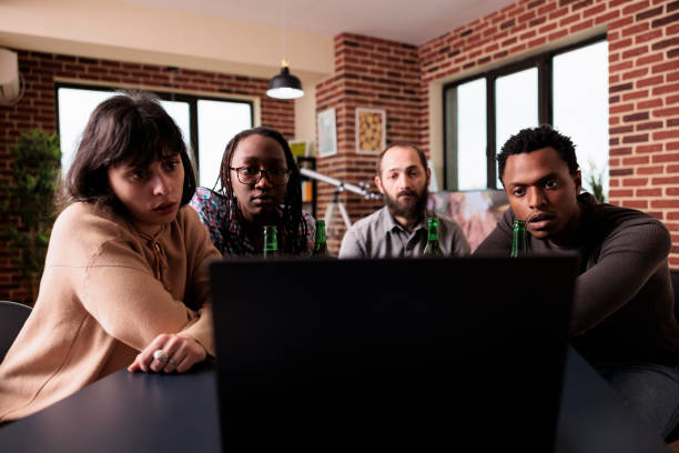 istock Diverse people sitting at table in living room while watching drama films together on laptop computer. 1446896607