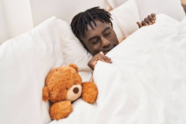 istock African american man lying on bed sleeping with teddy bear at bedroom 1446896796