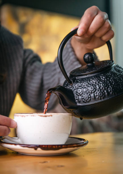 istock Woman in a cafe pour tea from a black cast iron teapot. 1446897431