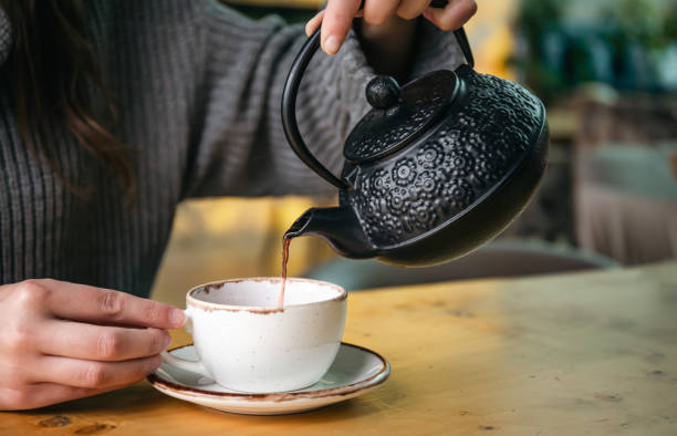 istock Woman in a cafe pour tea from a black cast iron teapot. 1446897457