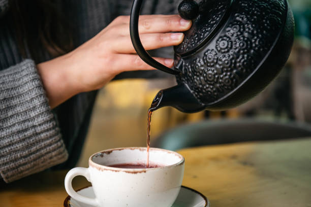 istock Woman in a cafe pour tea from a black cast iron teapot. 1446897458
