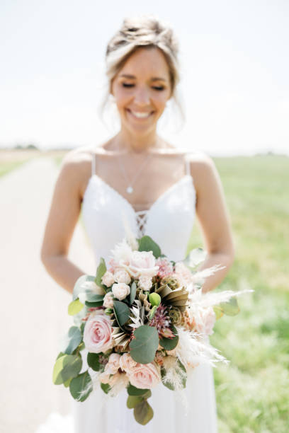 istock bride with bouquet stands on a field path and smiles 1446897562