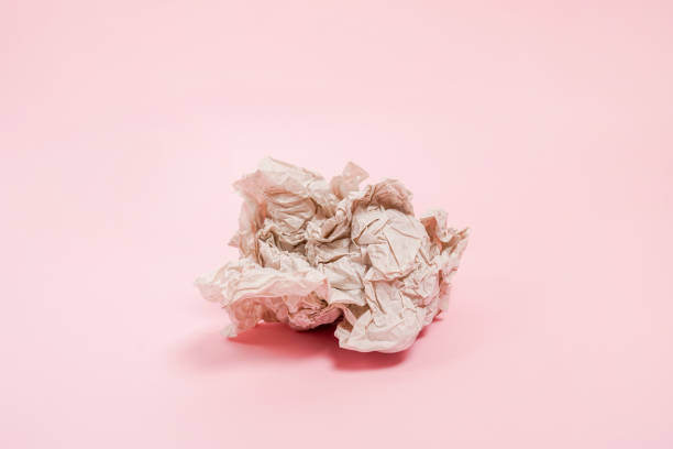 istock Crumpled paper ball laying on pink background 1446897568
