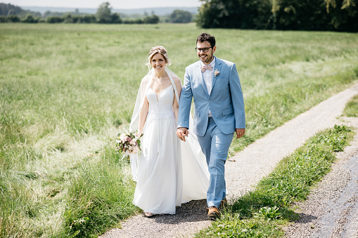 bride and groom walk on a field path in nature during photo shoot