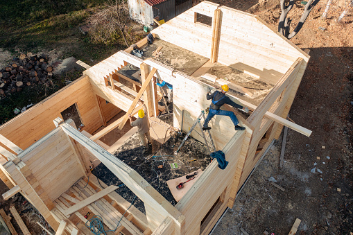 Aerial view of team of workers building a log cabin.