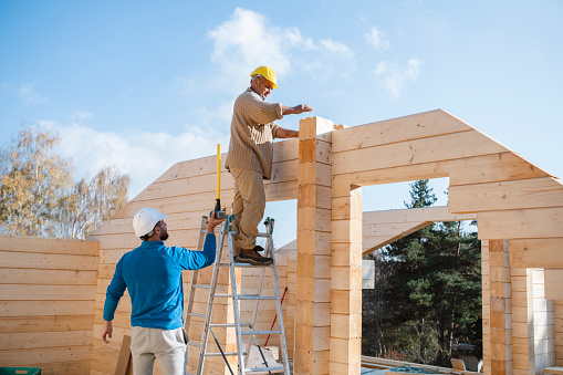 Team of construction workers building a wooden cabin.