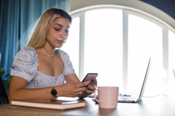 istock Young woman taking a moment to respond to a text message while working at her desk 1446901168