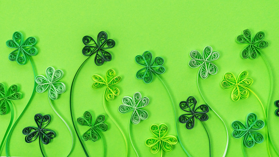 Shamrock leaves background in quilling technique for St. Patrick's Day. Green clover leaves for St. Patrick's Day banner. Concept of sustainable development and green energy background.
