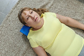 Portrait of pretty blondemature woman using foam roller for stretching exercise