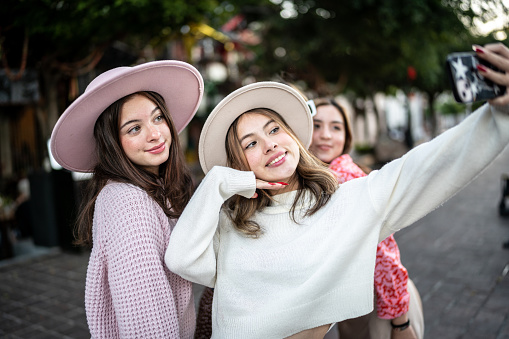 Young women taking selfies or filming using mobile phone outdoors