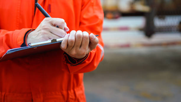 Writing on the safety checklist in audit. A safety officer is writing on the checklist document during safety audit workplace at the factory. Industrial expertise occupation working scene. Selective focus at hand's part. health and safety stock pictures, royalty-free photos & images