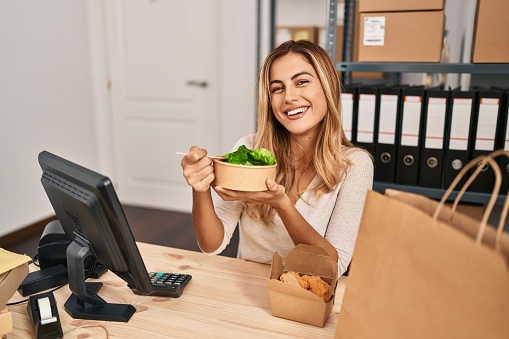 Young blonde woman ecommerce business worker eating salad at office