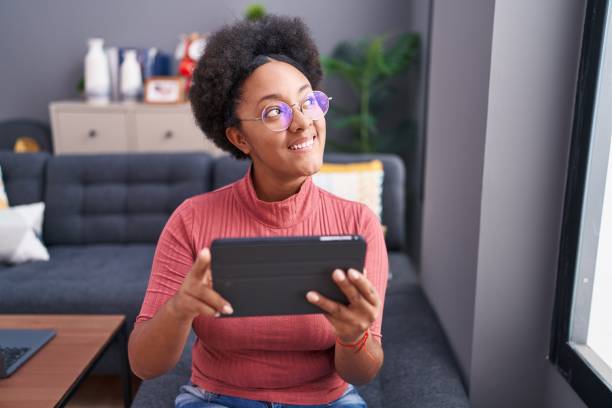 istock African american woman using touchpad sitting on sofa at home 1446909116