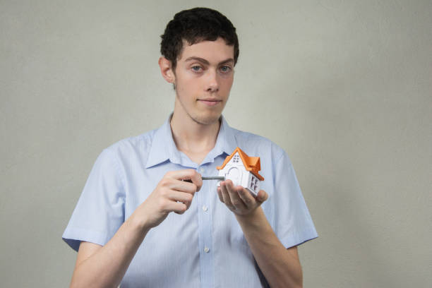 Happy young man holding a key and a miniature house