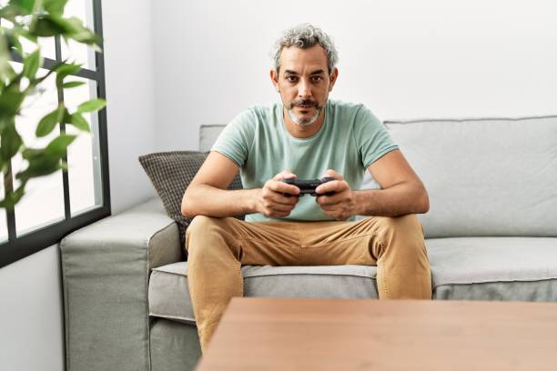 istock Middle age hispanic man playing video game sitting on the sofa thinking attitude and sober expression looking self confident 1446909588