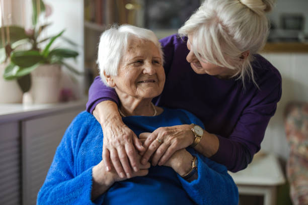 年老いた母親を抱きしめる女性 - ヘルスケアワーカー ストックフォトと画像