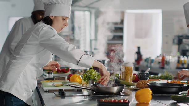 istock Female cook making professional culinary dish in frying pan 1446914130