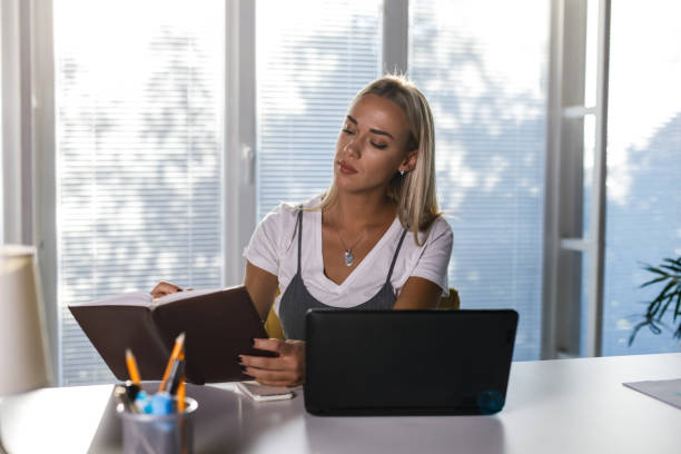 istock Young businesswoman checking her notebook for calendar and notes while working at her desk 1446914510