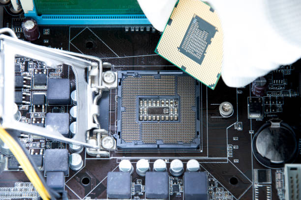istock Top view of motherboard and technician about to insert CPU chip. 1446917323