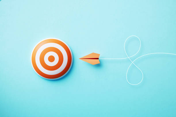istock Paper Plane Flying Towards A Bulls Eye Target On Blue Background 1446918902