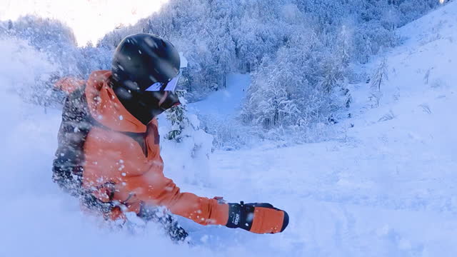 Snowboarder having fun snowboarding backcountry on a beautiful winter day